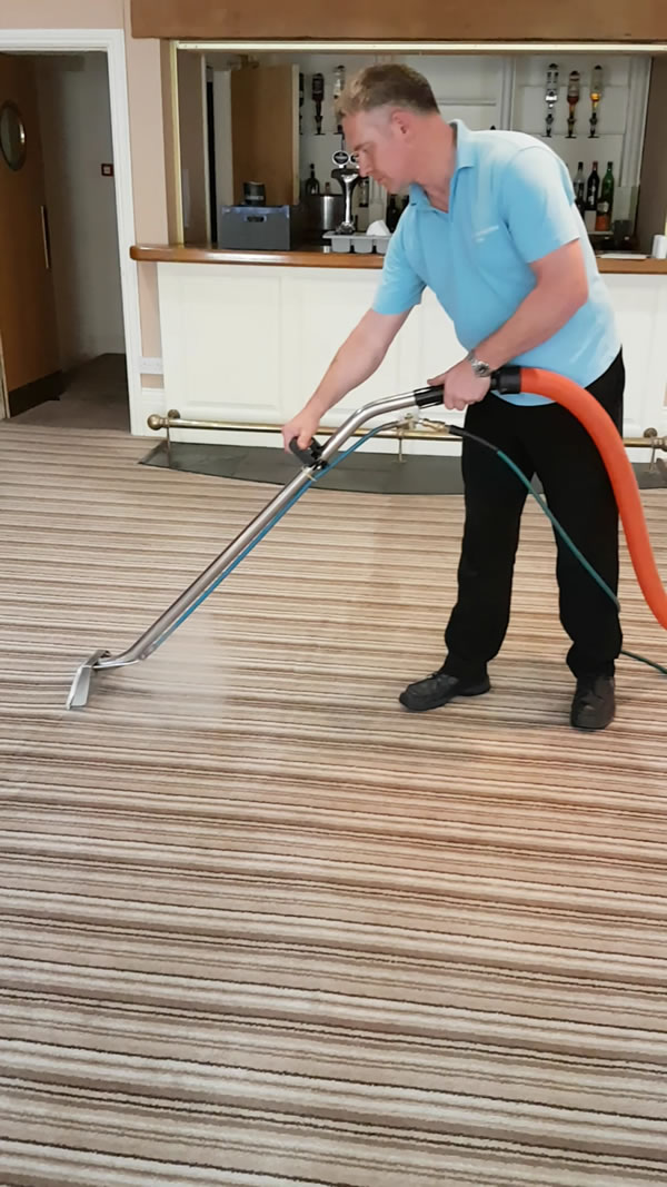 James, the owner of Carmarthenshire Carpet Care steam cleaning a carpet in a bar area.