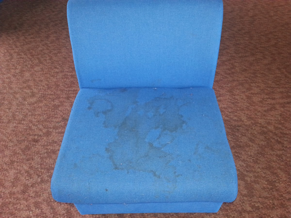 Image shows a badly stained upholstered chair before cleaning.